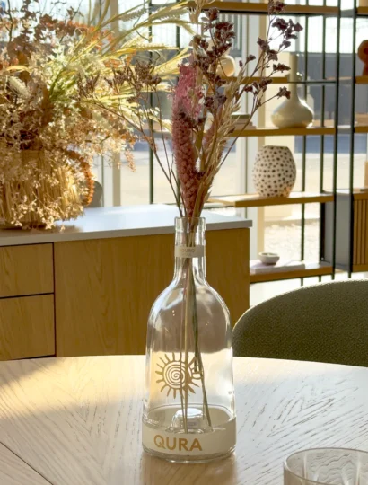 A Garrafa Qura, de design sustentável, é reutilizada como jarra de flores na mesa elegante