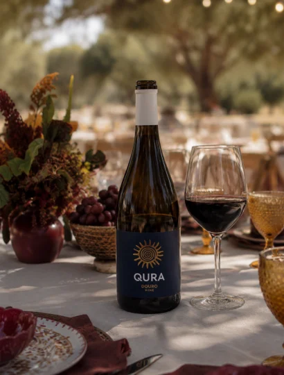 Garrafa de vinho Qura Red sobre mesa elegantemente posta com copos e pratos decorativos